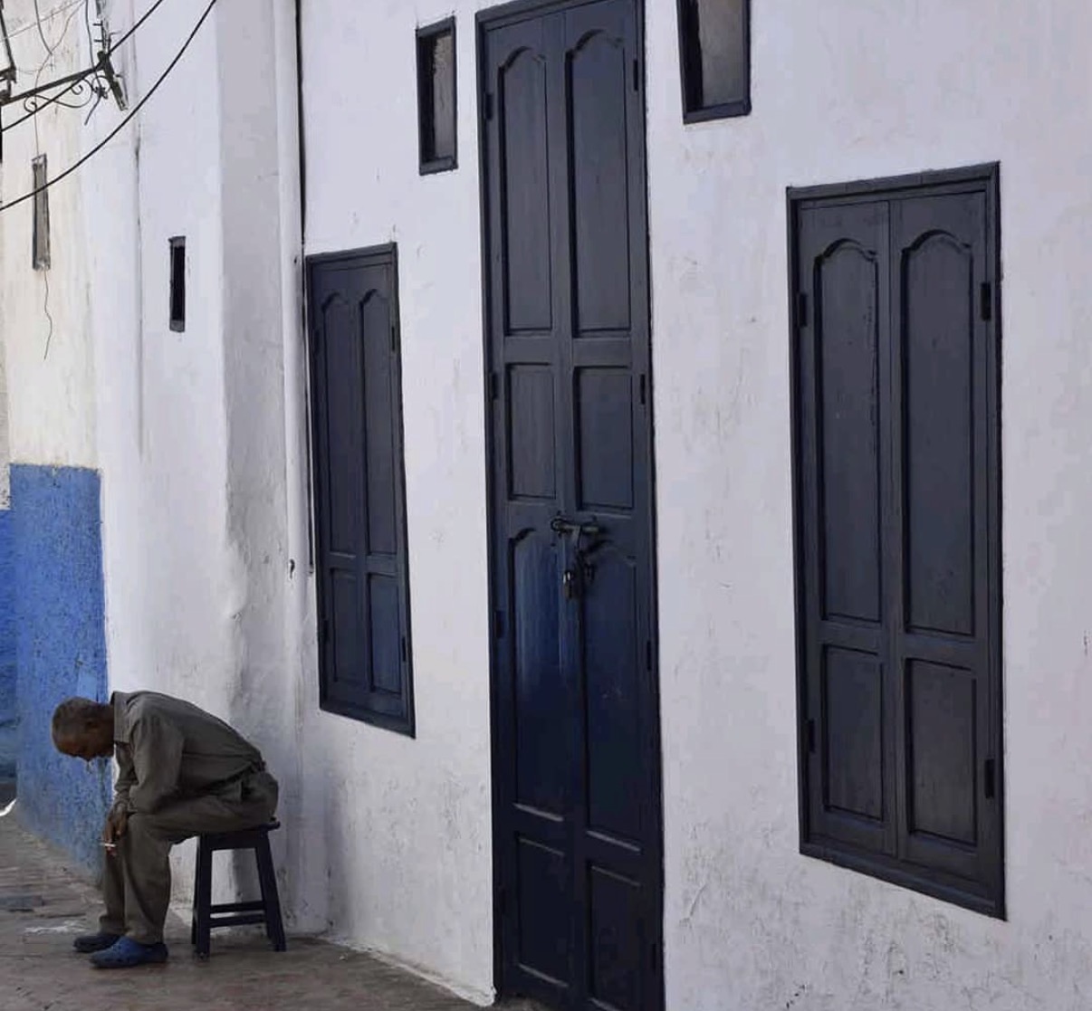 Indigo panelled doors and a man on a stool in a Moroccan medina, from the Uncovering Morocco research