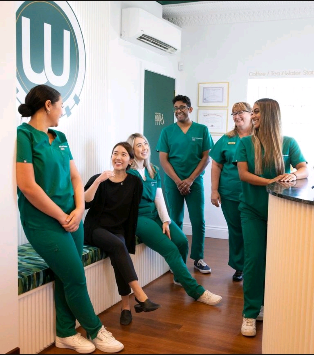 Wired Orthodontics team beneath the illuminated monogram in the waiting lounge