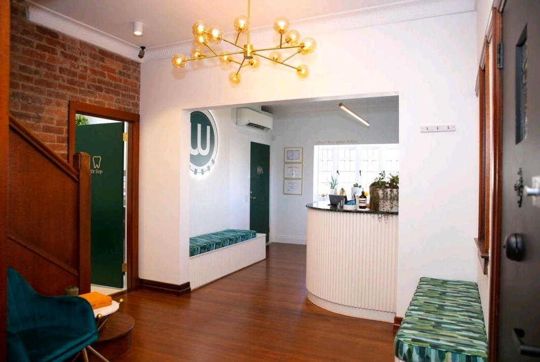 Wired Orthodontics entry foyer with brass chandelier, exposed brick and curved reception desk